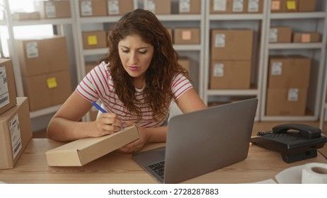 Kvinna skriver på ett paket vid ett skrivbord med en laptop och lagerhyllor i bakgrunden.