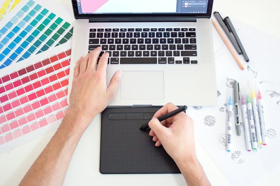 Person arbetar med grafisk design på laptop och ritplatta